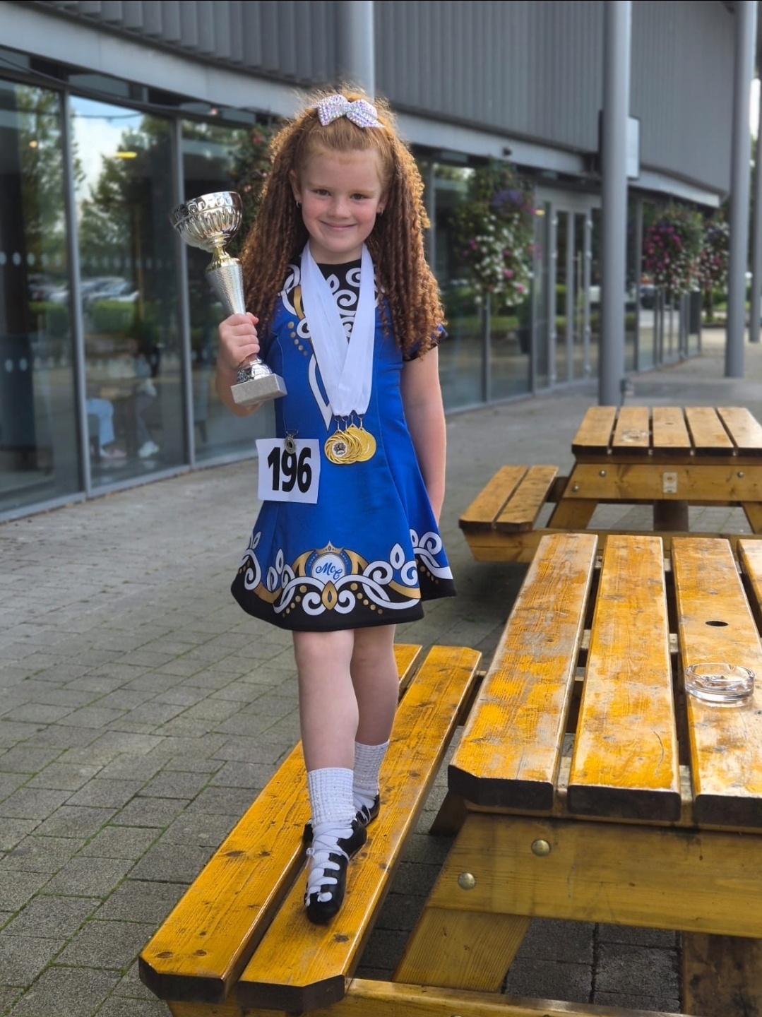 Young dancer proudly holding her trophy and medals